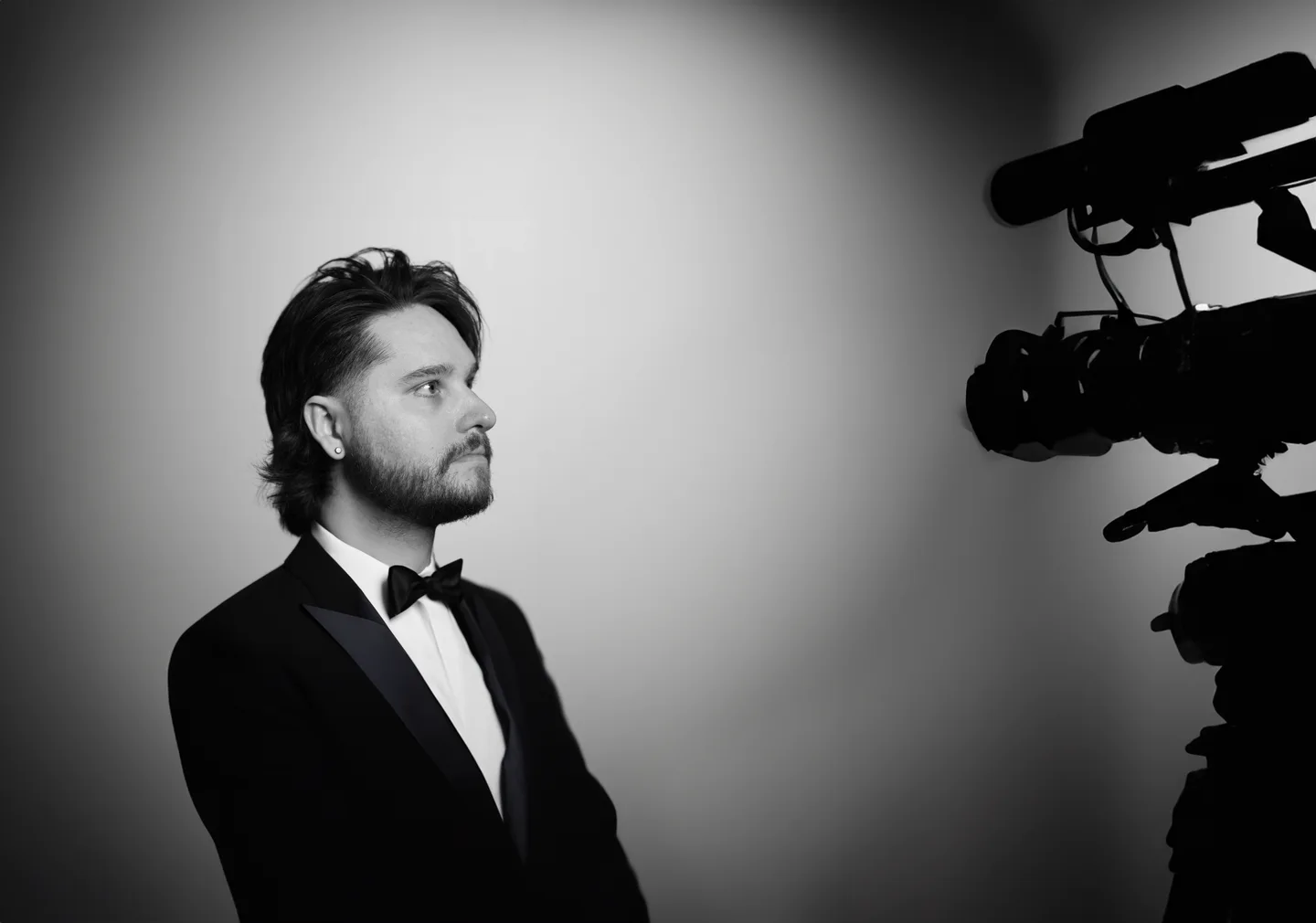 Black and white creative portrait of Matt beside a film camera